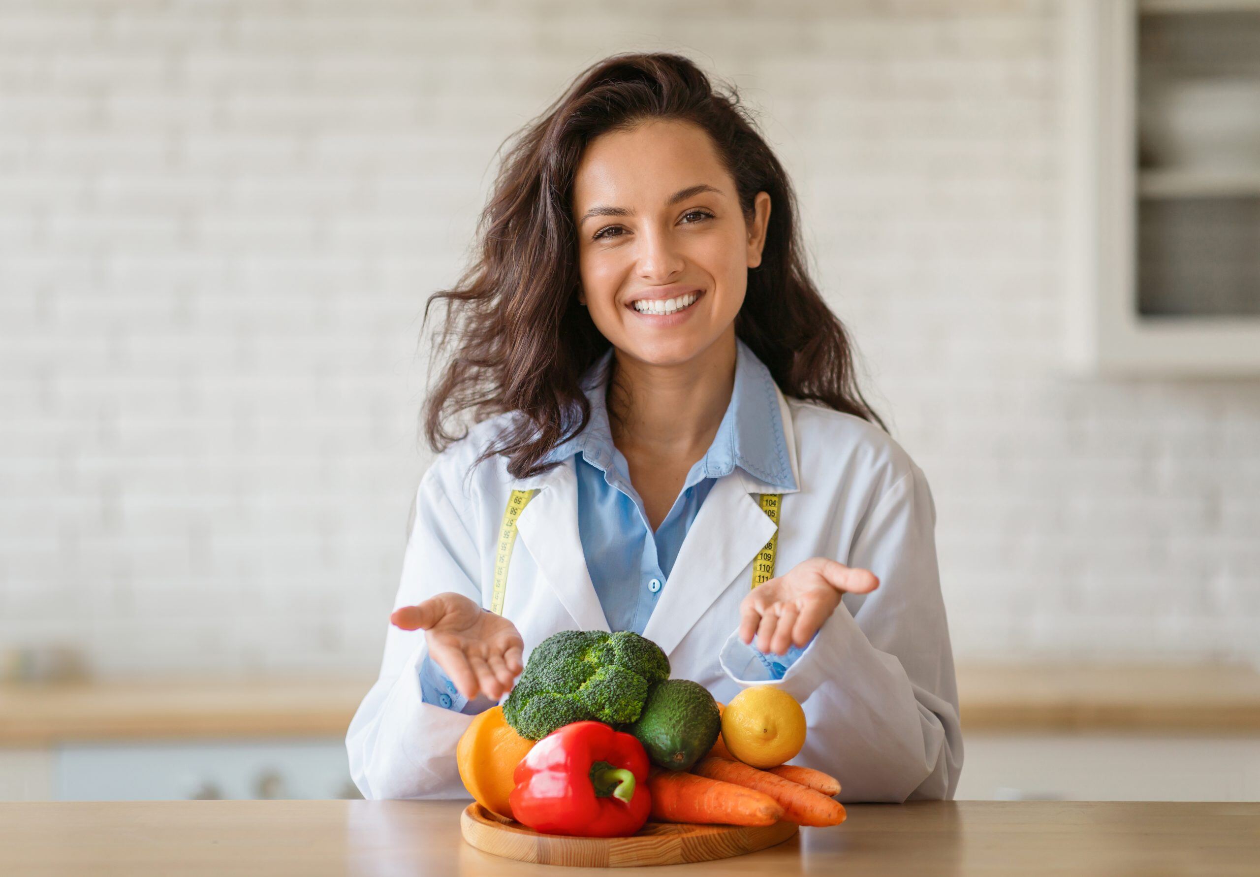 portrait-of-cheerful-dietitian-in-lab-coat-pointin-2023-11-27-05-11-36-utc-scaled